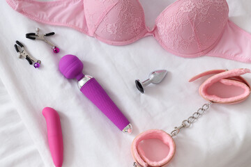 Sex toys with bra on bed, top view