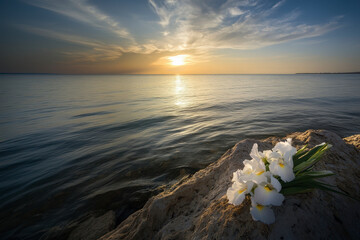Black funeral ribbon and white irises flowers on a rock by the calm sea