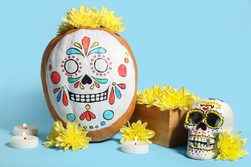 Pumpkin with painted skull, burning candles and flowers on color background. El Dia de Muertos