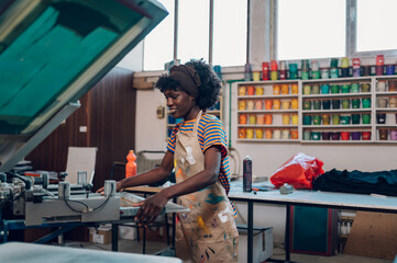 Side view of diverse graphic specialist putting frame on printing press