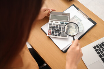 Female teacher with magnifier and bribe at table, closeup. Corruption concept