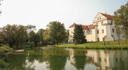 Historic Castle by a Serene Riverbank with Reflections in the Water and Lush Greenery