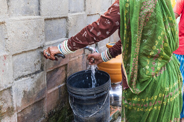 Filling a bucket with drinking water at a public tap. © Emily_M_Wilson