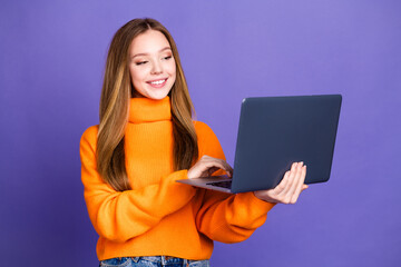 Naklejka premium Portrait photo of youth charming blonde hair cute happy smile girl in orange turtleneck studying online with laptop isolated on violet color background