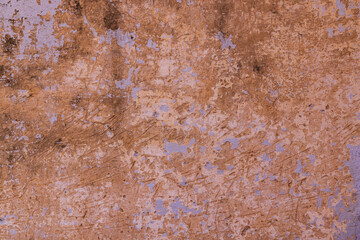 Peeling paint on an orange stucco wall.