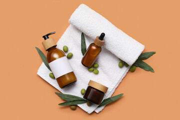 Set of natural cosmetic products, clean towel and green olives on color background