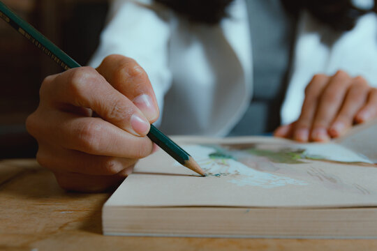 Close-up of female hand drawing in a notebook with pencil