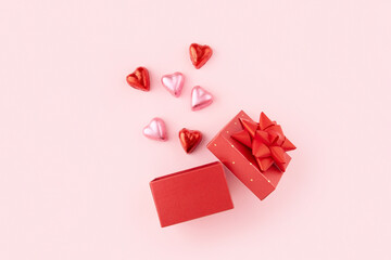 Red gift box for Valentines Day on the pink background with heart shaped candies 