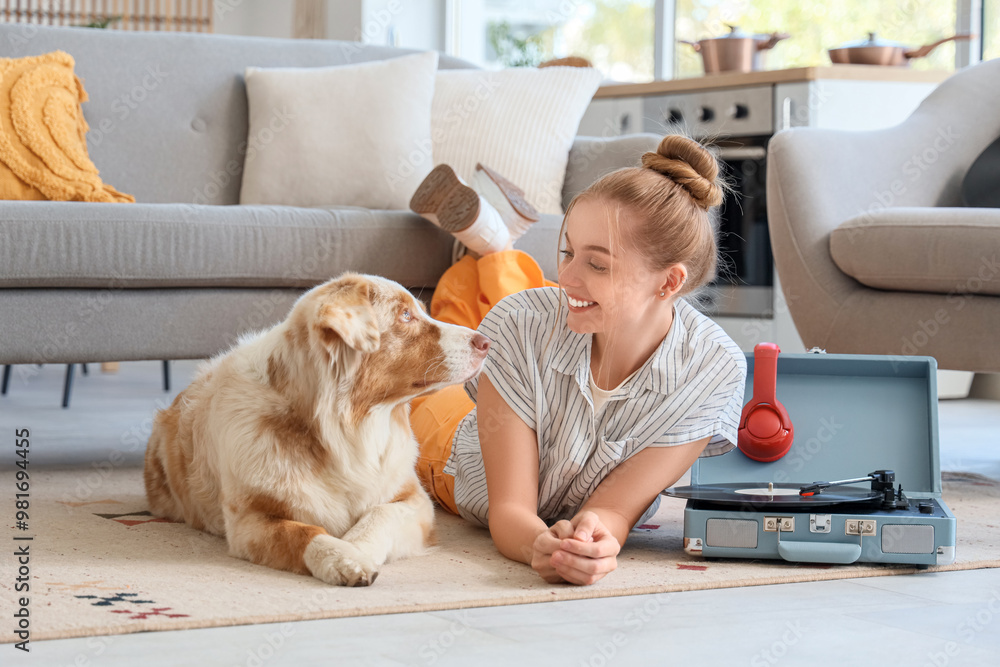 Poster Young woman with Australian Shepherd dog and record player lying on floor at home