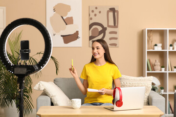 Young woman with notebook recording podcast at home