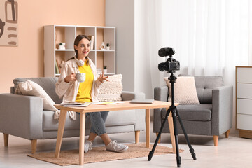 Young woman with cup of tea recording podcast at home