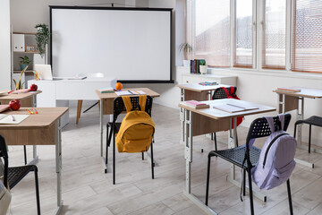 Interior of classroom with school desks and projector screen