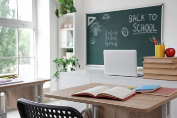 School desk with notebooks in empty classroom