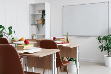 Interior of empty classroom with school desks and clean whiteboard