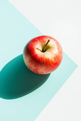 Top view of an apple on a white and light blue background, with hard shadows, in a minimalist style. This is a studio photography product shot with bright light, sharp focus, and professional 