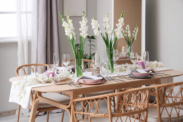 Beautiful table setting with white Gladiolus flowers and burning candles in room