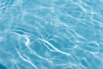 Blue water with ripples on the surface. Defocus blurred transparent blue colored clear calm water surface texture with splashes and bubbles. Water waves with shining pattern texture background.