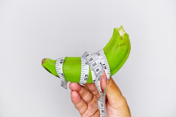  banana wrapped around a centimeter measuring device on a white background