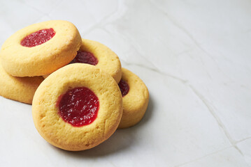 Stack of Thumbprint Cookies with Red Jam Filling on Marble Surface
