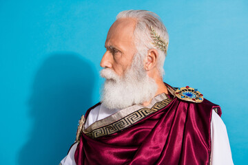 Photo of handsome senior male look strict empty space profile wear ancient greek god king dress isolated on blue color background