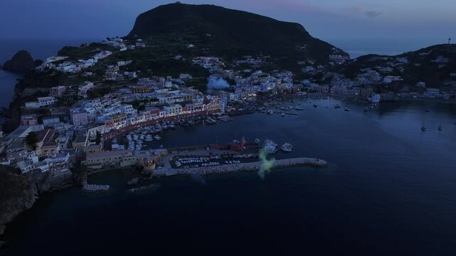 Fireworks going off over a small town on an Island off Italy's coast. Shot from a drone at dusk