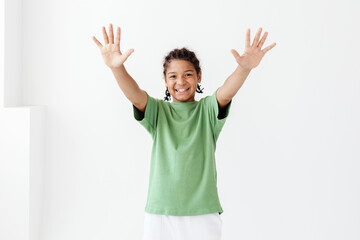 Excited young boy in green tshirt joyfully raising hands in the air energized by success