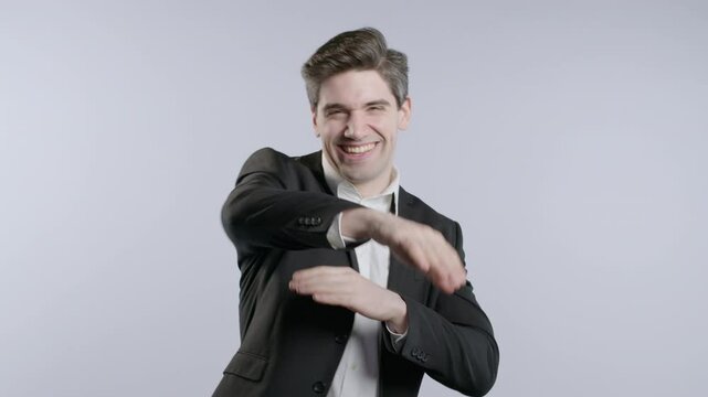 Brunette positive businessman listening music and dancing, white studio background. Radio, wireless modern sound technology, online player. Corporate worker have fun. 