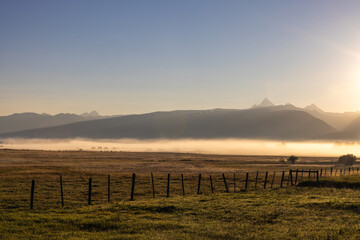 Photograph of beautiful peaceful foggy morning on a ranch in Idaho Grand Teton Mountains on the horizon