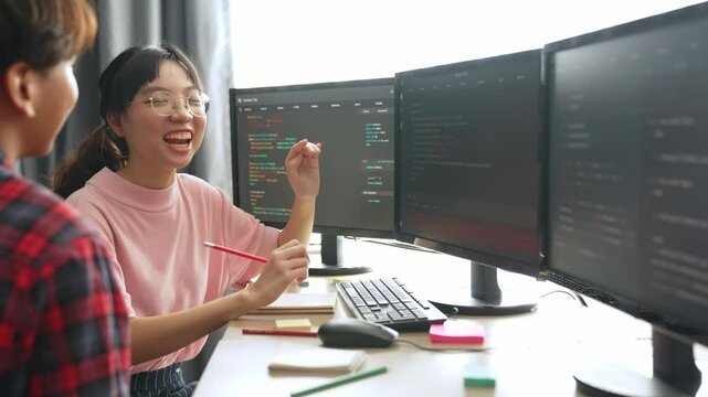 Slow motion back end software developer engineer for computer programming working together on debugging writing computing code, solving complex algorithms display on monitor in office. Burgeoning