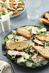 Delicious Caesar salad with chicken on grey textured table