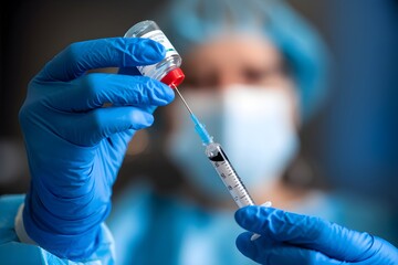 Blue gloved hands filling syringe from vial, sterile focus with blurred background