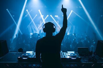 Silhouette DJ with raised hand behind turntable, glowing blue lights