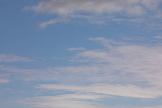 Pastel color pinkish clouds covering a light blue sky on bright day 