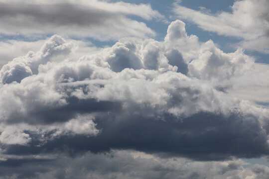 Multiple types of clouds at different levels fully covering the bright blue sky, Cloudscape photo.