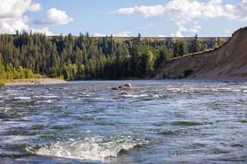 Photo taken from middle of Snake River rapids and rocky shoreline on a beautiful bright day in the Grand Teton national park