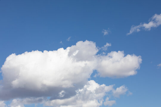 Photo of white fluffy Cumulus clouds and bright blue sky background