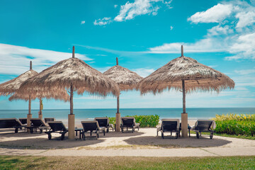lounge chairs on the beach under a thatched umbrella