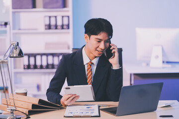 Obraz premium Serious trader using mobile phone app on smartphone for checking stock trading data analysis concept, focused businessman holding cellphone working in office with financial graph on computer monitors