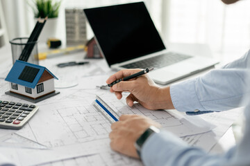 Architect working drawing draft on blueprints in the office, working with modern house blueprint floorplans, architectural and construction project concept.