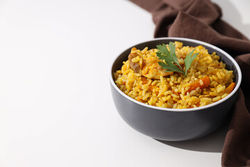 Pilaf in bowl and towel on white background, space for text