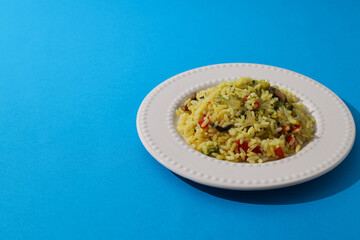 Pilaf on plate on blue background, space for text