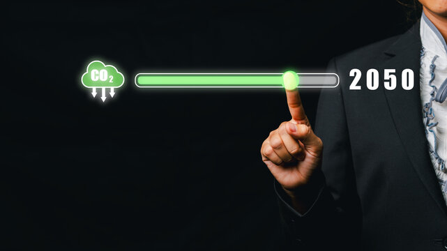 Businessperson pointing at a carbon neutrality progress bar with a CO2 emission reduction target for 2050, symbolizing environmental sustainability and climate action.