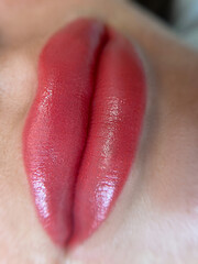 permanent makeup on the lips of a young woman of a delicate peach shade close-up, a girl after a cosmetic procedure with smooth and clean healthy skin.	
