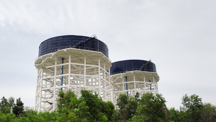 Elevated water tanks surrounded by greenery under a cloudy sky