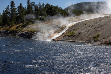 Excelsior geyser runoff hot steam rising from the water flow cascading falling into the firehouse river at Yellowstone national park in Wyoming