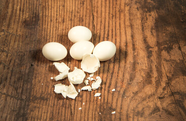 Peeled fresh organic eggs isolated on a rustic wooden table with advertising space.
