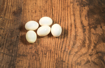 Peeled fresh organic eggs isolated on a rustic wooden table with advertising space.