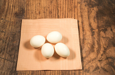 Peeled fresh organic eggs isolated on a rustic wooden table with advertising space.