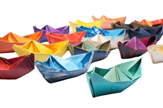 A collection of different paper boats of various colors and designs, arranged artistically on a white background