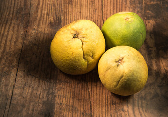 Beautiful yellow and green ripe Pomelo fruit isolated on a rustic wooden table. 